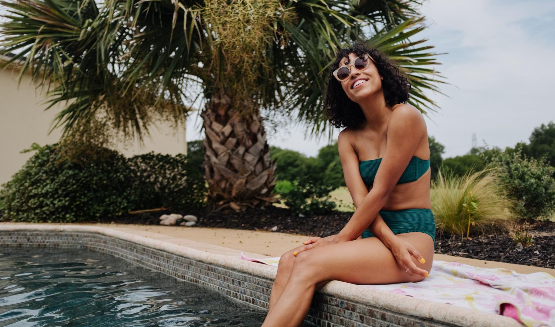 a woman sitting on a ledge by a pool