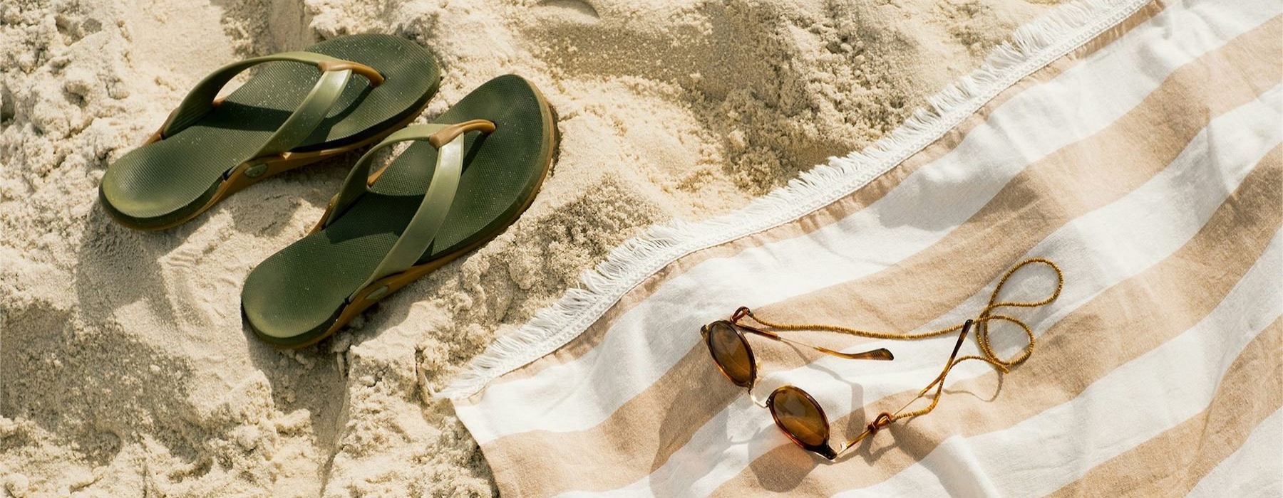 pair of sandals, a towel, and sunglasses on the beach