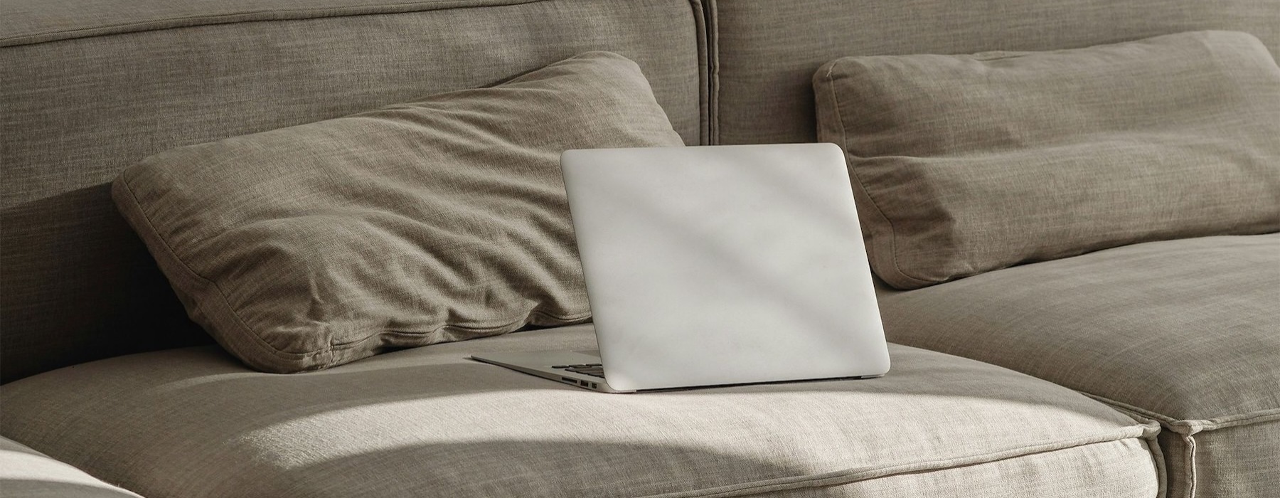 a couch with pillows and a laptop